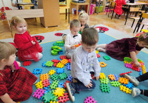 Dzieci z grupy "Biedronki" układają na dywanie budowle z nowych klocków