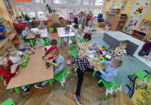 Dzieci z grupy "Misiaczki" bawią się przy stolikach nowymi zabawkami od Mikołaja