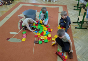 Chłopcy z grupy "Żabek" budują konstrukcje na dywanie z nowych klocków