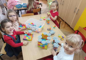 Dzieci z grupy "Słoneczek" układają przy stoliku nowe klocki