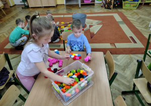 Emma i Kuba z grupy "Żabek" układają przy stoliku budowle z nowych klocków