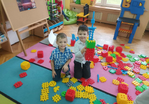 Szymon i Tymon z grupy "Słoneczek"układają na dywanie budowle z nowych klocków