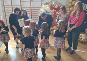 Dyrektor szkoły wręcza dziewczynkom dyplomy.