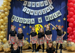 „ Radosne kroczki” stoją na tle dekoracji konkursu.