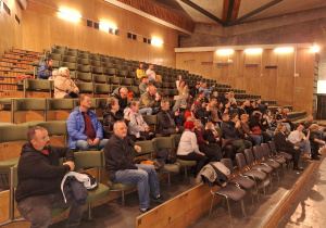 Rodzice przedszkolaków siedzą na widowni i obserwują swoje dzieci.