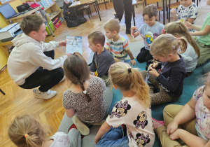 Bartosz pokazuje dzieciom swoje dyplomy z konkursów