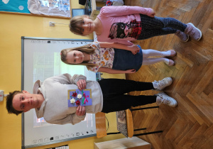 Starszaki wraz z młodym łyżwiarzem trzymającym laurkę