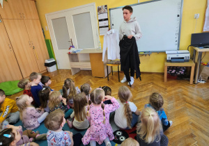 Młody łyżwiarz pokazuje przedszkolakom swój strój do występów na lodzie