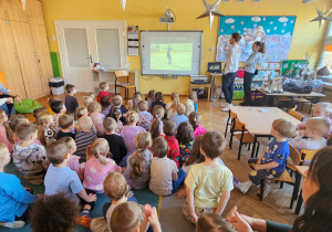 Przedszkolaki oglądają filmik z występu łyżwiarza
