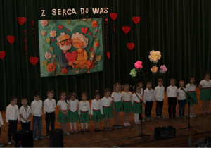 Grupa „Krasnoludków” śpiewa piosenkę „Babcia od bajek, dziadek od zagadek”.