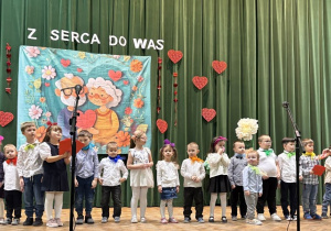 „Żabki” z laurkami czekają na scenie na babcie i dziadków.