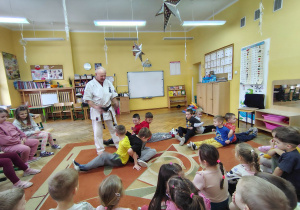 Chłopcy siedzą tyłem do siebie, połączeni rękoma, próbują wstać bez odrywania rąk.