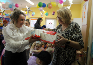 Pani Dyrektor na ręce Pani Ani przekazuje słodkie upominki dla dzieci z grupy Biedronek.