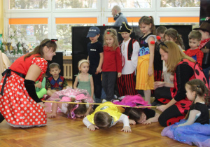 Dzieci pełzają pod bardzo nisko obniżoną wstęgą.