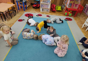 Dzieci naśladują pączki podczas zabawy ruchowej "Turlające pączki"