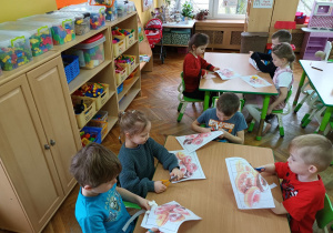 Misiaczki wycinają paskowe puzzle przedstawiające pączki.