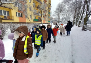 Krasnoludki spacerują w otoczeniu zimowej pory roku.