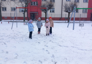 Przedszkolaki stoją w śniegu.