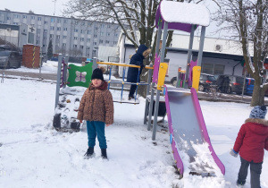 Hania stoi obok zjeżdżalni.