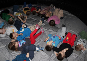 Dzieci leżąc oczekują na projekcję filmu.