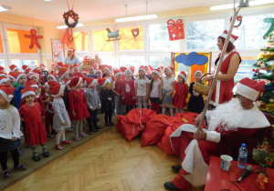 Wszystkie przedszkolaki stoją przed Mikołajem i śpiewają.