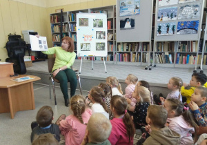 Pani Ilona przedstawia dzieciom książkę z ciekawostkami o kotach.