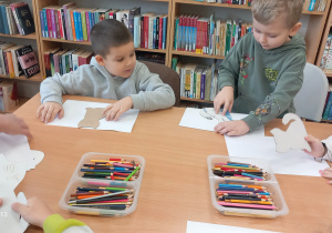 Chłopcy odrysowują szablony kotów.