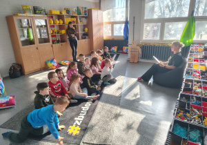 Przedszkolaki siedzą na macie i słuchają bajki.