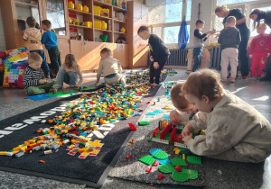 Dzieci podczas zabawy układania budowli z klocków Lego.