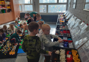 Dzieci budują na dywanie, Olek i Antek wybierają klocki.