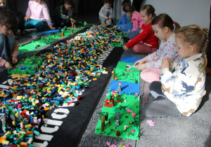 Przedszkolaki budują z klocków Lego.