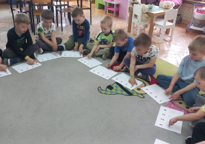 Chłopcy wystukują rytm palcami po wzorze na kartkach.