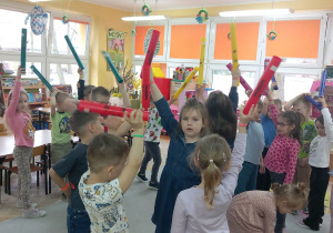 Krasnoludki trzymają Bum bum rurki w górze.