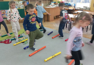 Dzieci chodzą rytmicznie między rurkami.