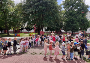 Przedszkolaki tworzą długi pociąg.