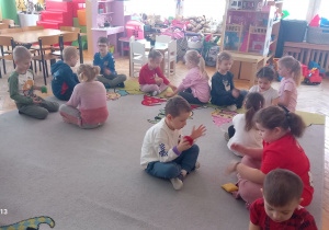 Przedszkolaki podają sobie woreczek siedząc naprzeciwko siebie.