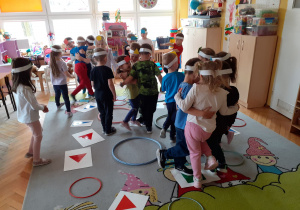 Grupki dzieci stoją na figurach na jednej nodze.