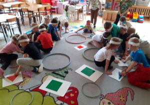 Dzieci dotykają figur na podłodze.