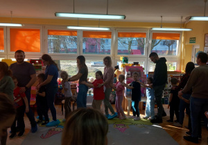 Rodzice wspólnie z dziećmi bawią się w pociąg.