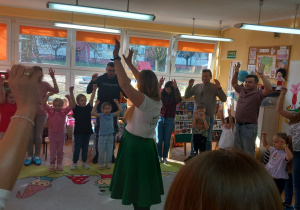 Pani Karolina trzyma ręce w górze wraz z uczestnikami.