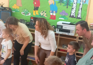 Rodzice i dzieci uderzają rękami w nogi.