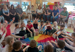 Dzieci siedzą na chuście animacyjnej.