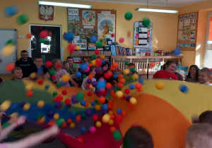 Dzieci podrzucają piłeczki na chuście.