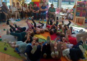 Krasnoludki leżą na chuście i unoszą nogi w górę.