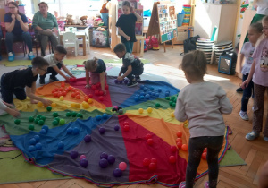 Przedszkolaki segregują piłeczki kolorami.