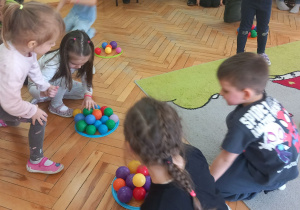 Dzieci układają piłeczki w obręczy i przeliczają je.