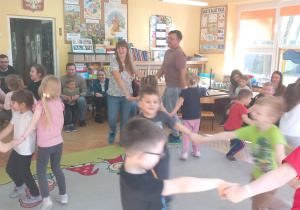 Dzieci i rodzice tańczą kilkuosobowych kółeczkach.