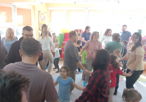 Rodzice i dzieci tańczą w kółeczkach.