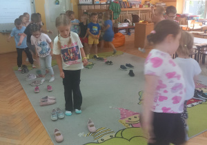 Przedszkolaki chodzą po dywanie według kodu zapisanego kapciami.