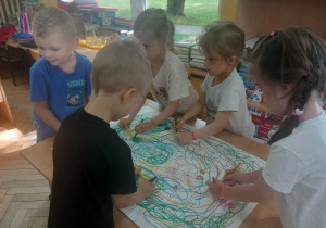 Dzieci chodzą wokół stołu i kreślą koła.